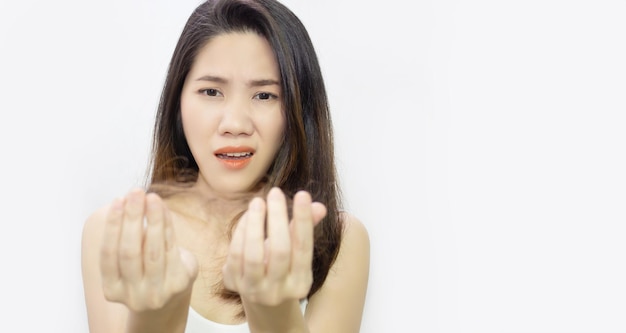 A mulher asiática está procurando a perda de cabelo na mão com cara de preocupação