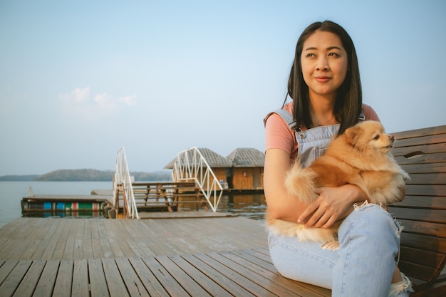 A mulher asiática feliz aprecia relaxa com seu cão.