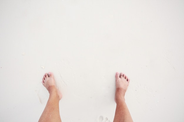 A mulher asiática tem a pele bicolor do pé com banho de sol na praia e no mar brancos