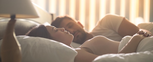 Foto a mulher atraente dormindo perto de um homem na cama confortável à noite