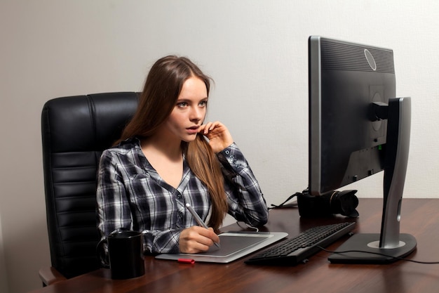 A mulher atrativa está retocando fotos digitais operando o computador