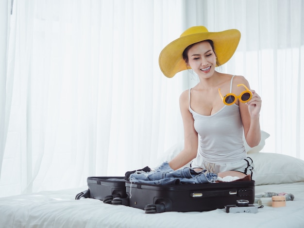 A mulher bonita asiática está preparando sacos para ir de férias