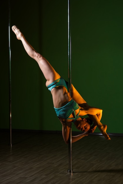 A mulher bonita dança perto de um polo em um fundo colorido.