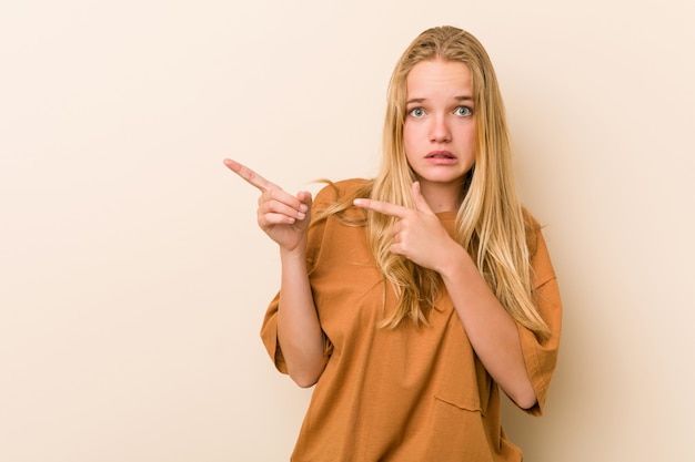 Foto a mulher bonito e natural do adolescente chocou apontar com indicadores para um espaço em branco.