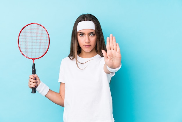 A mulher caucasic nova que joga o badminton isolou a posição com a mão estendida que mostra o sinal de parada, impedindo-o.