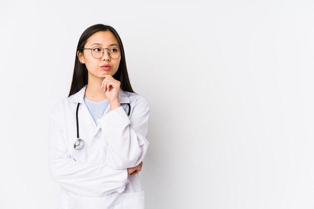 A mulher chinesa do doutor novo isolou a vista lateralmente com expressão duvidosa e cética.