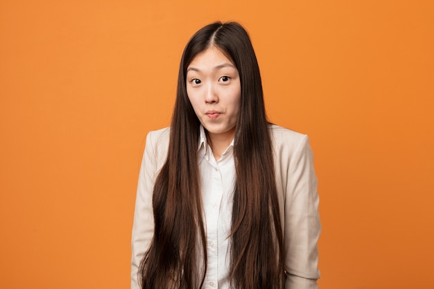 A mulher chinesa do negócio novo encolhe os ombros e abre os olhos confusos.