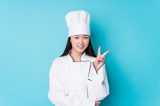 A mulher chinesa nova do cozinheiro chefe isolou mostrar o número dois com dedos.