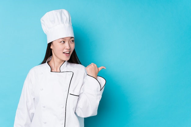 A mulher chinesa nova do cozinheiro chefe isolou pontos com o dedo do polegar afastado, rindo e despreocupado.