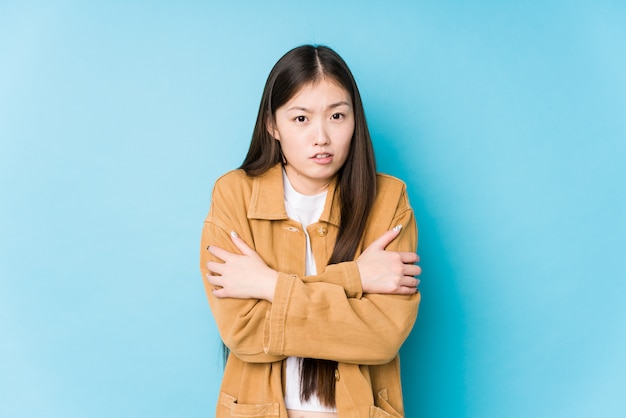 A mulher chinesa nova que levanta em uma parede azul isolou ir frio devido à baixa temperatura ou uma doença.