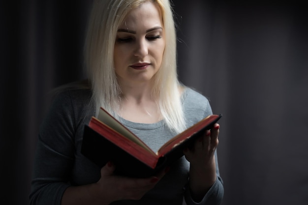 Foto a mulher coloca os braços no colo e abre o livro para ler.