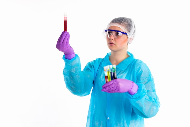 A mulher com tubos diferentes está se concentrando em um líquido vermelho em um tubo em um fundo branco.