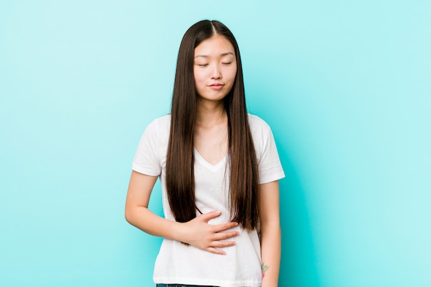 A mulher consideravelmente chinesa nova toca na barriga, sorri delicadamente, comendo e conceito da satisfação.