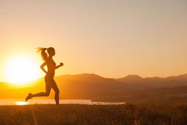 A mulher corre nas montanhas no oceano.