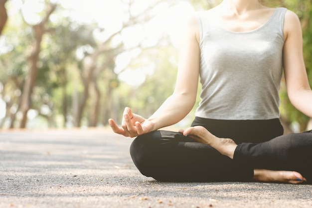 Foto a mulher da aptidão está meditando nas ruas no parque.