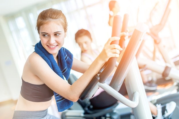 A mulher de esporte caucasian gosta de exercitar-se com treadmill no centro de ginástica com grupo de pessoas