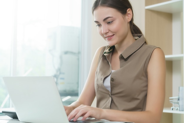 A mulher de negócio trabalha no computador portátil no escritório que pensa sobre seu negócio.