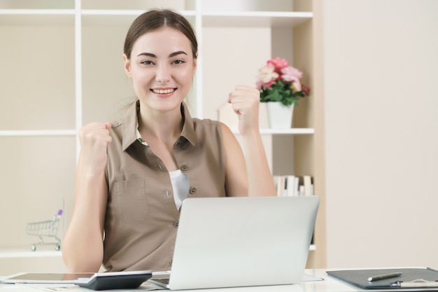 A mulher de negócio trabalha no computador portátil que expressa o sentimento bem sucedido.