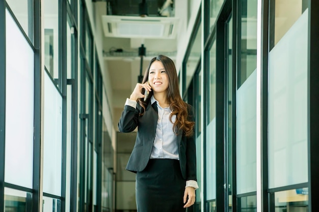 A mulher de negócios asiática faz um telefonema no escritório