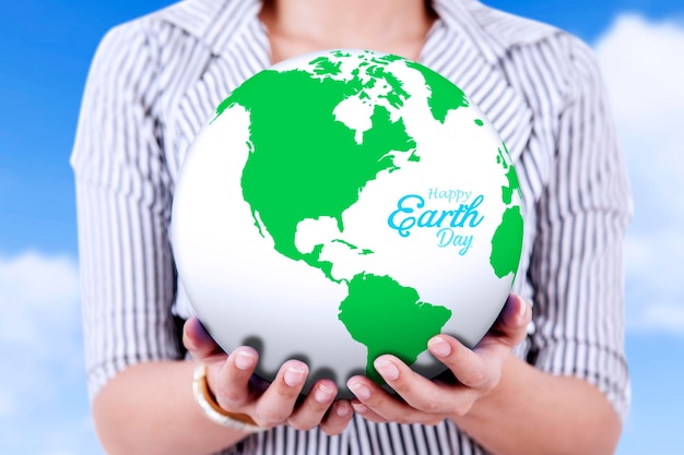 A mulher de negócios segura o globo com o texto feliz do Dia da Terra