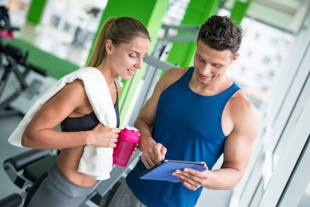 Foto a mulher discute com um instrutor de fitness com um tablet