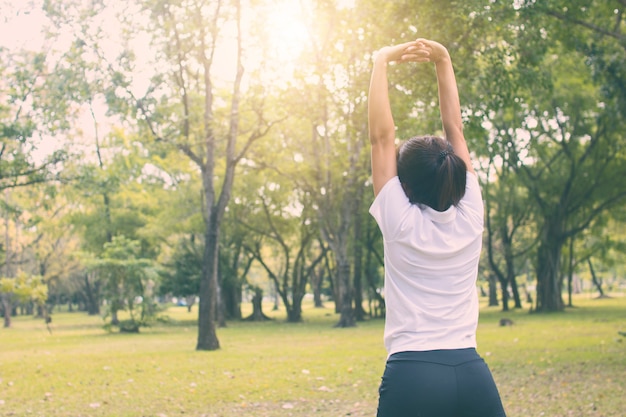 A mulher do esporte worm acima no parque na manhã, elabora e exercita o conceito