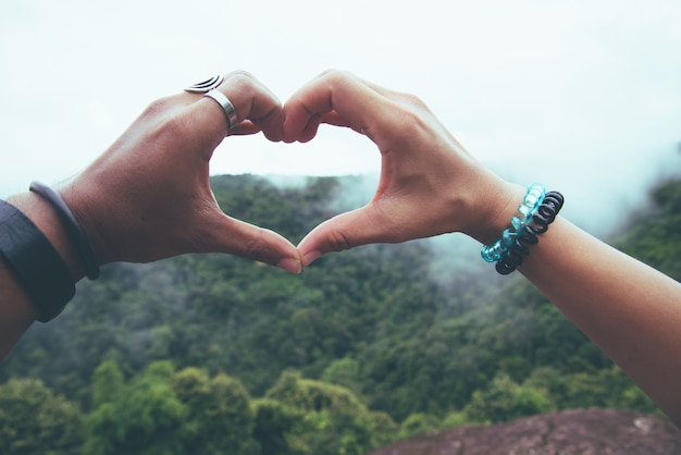 A mulher e a mulher asiáticas dos pares do amante viajam natureza. mão em forma de coração. Com a natureza