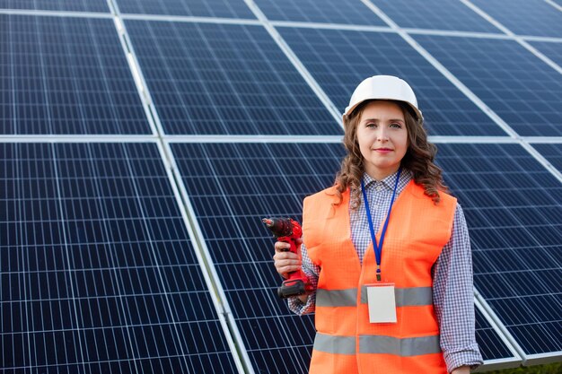 A mulher eletricista com chave de fenda na estação solar