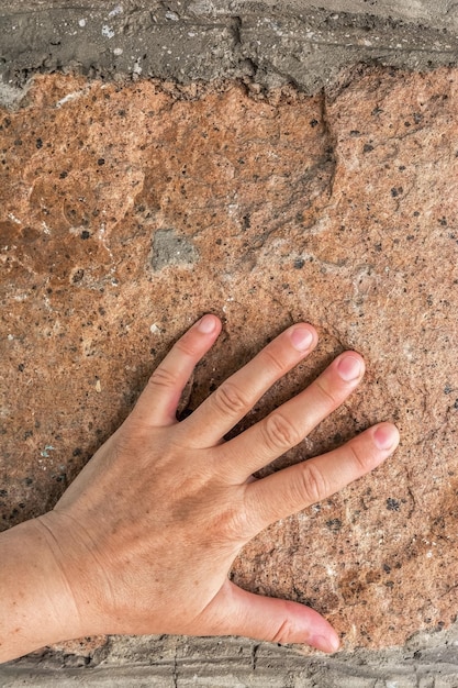 a mulher encostou a palma da mão na parede de pedra