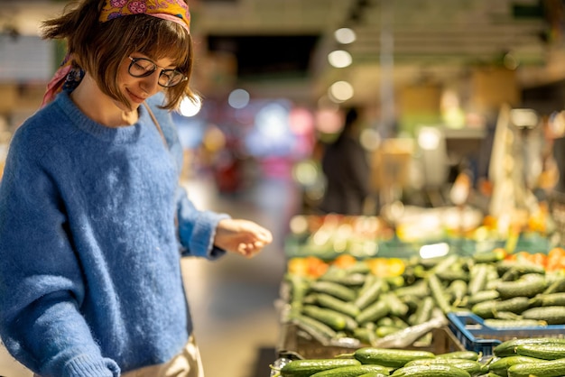 A mulher escolhe vegetais no supermercado