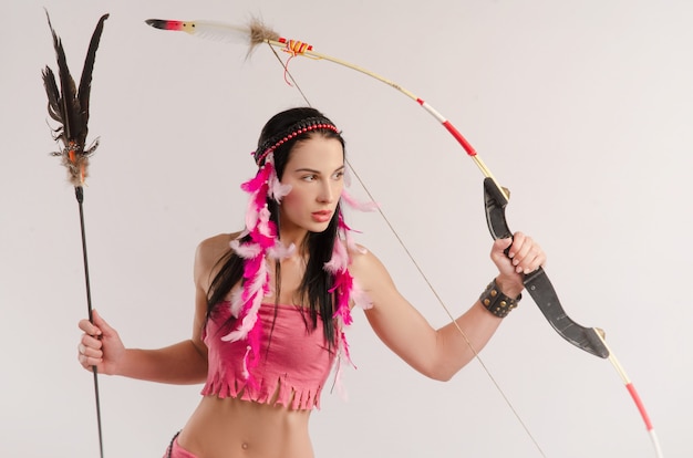 A mulher esguia em uma fantasia de amazona com um arco e flecha nas mãos