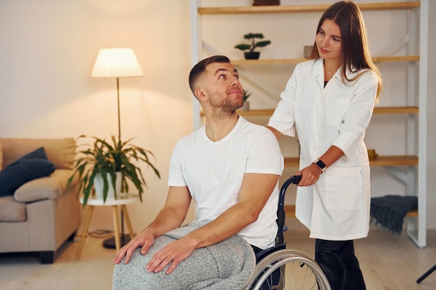 A mulher está ajudando o homem deficiente na cadeira de rodas está em casa