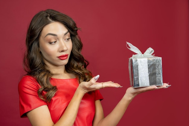 Foto a mulher está desapontada com o presente em um fundo vermelho