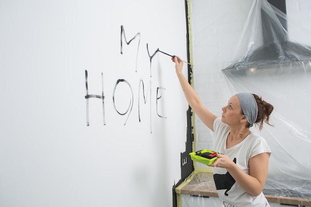 A mulher está escrevendo na parede da minha casa A mulher está pintando a parede com tinta preta