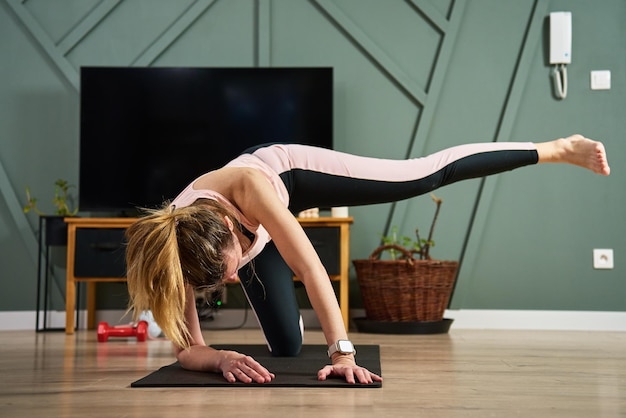 A mulher está fazendo exercícios esportivos na sala de estar, treinamento esportivo e conceito de fitness, estilo de vida saudável