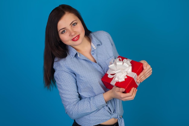 A mulher está feliz com um presente em suas mãos contra o fundo azul