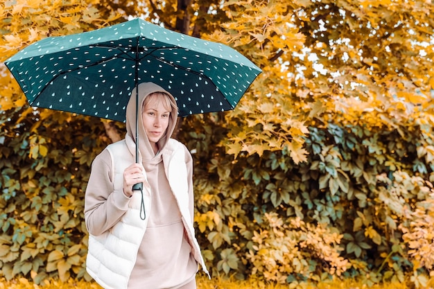 A mulher está no parque de outono com um guarda-chuva Atmosfera de outono