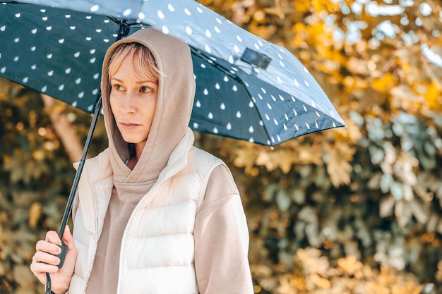 A mulher está no parque de outono com um guarda-chuva Atmosfera de outono