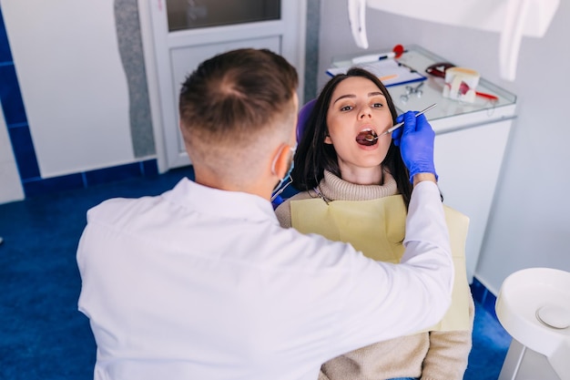 A mulher está sendo examinada pelo dentista na clínica odontológica O dentista