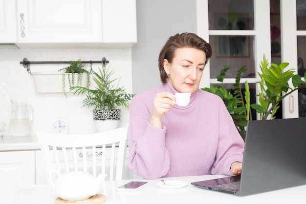 A mulher está trabalhando com laptop em casa online