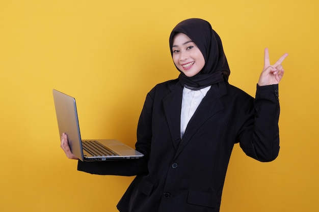 A mulher estava vestindo um terno preto e calça escura, segurando um laptop apontando para cima