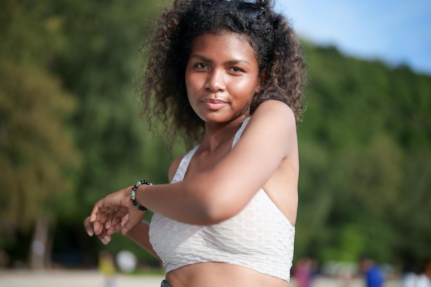 A mulher exercita e estica os músculos antes do treino ao ar livre Retrato sexy senhora africana asiática preparando-se para fitness na praia