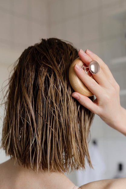 A mulher faz uma automassagem na cabeça para o crescimento do cabelo