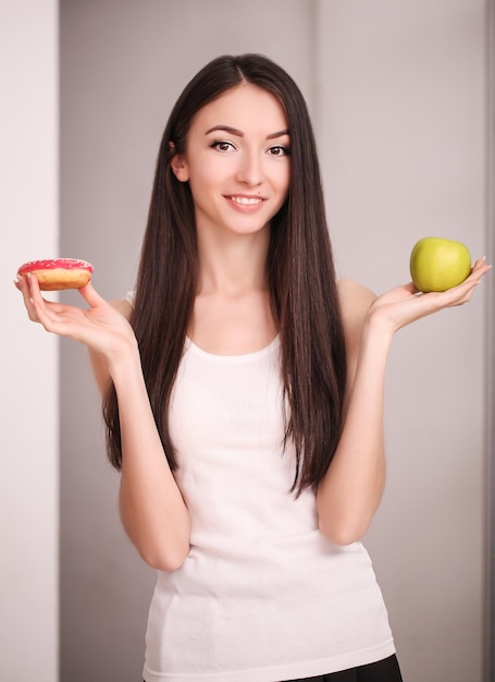 A mulher faz uma escolha entre uma maçã e um donut