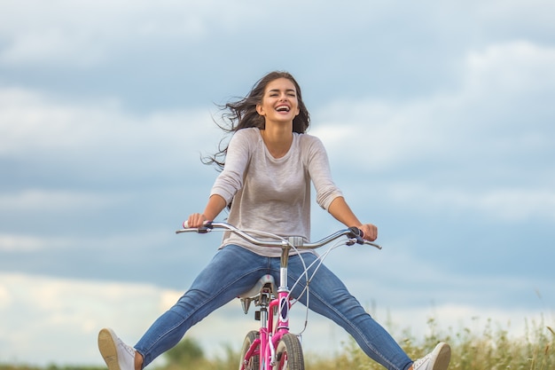 Foto a mulher feliz anda de bicicleta ao ar livre