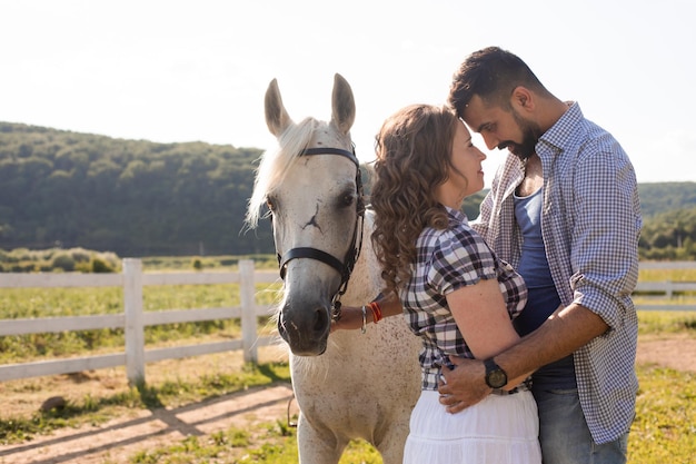 A mulher feliz com seu namorado fica ao lado de um cavalo