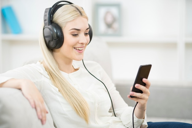 A mulher feliz escuta a música nos fones de ouvido e segura um fonej