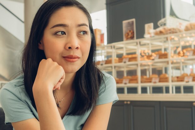 A mulher feliz está sentada e espera por alguém no café da padaria.