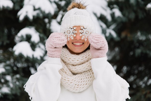 A mulher feliz no inverno branco veste guardarar um floco de neve bonito em um parque.