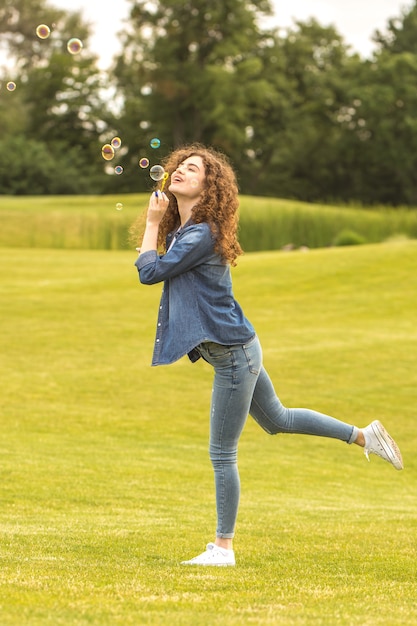A mulher feliz soprando bolhas no parque